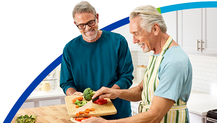 Two senior males cooking a healthy meal in the kitchen.​​ 
